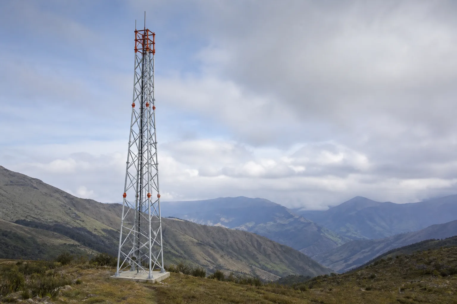 Torre metálica autosoportada completa en un paisaje montañoso, visual de referencia generado